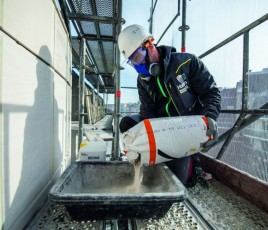 Maçon manipulant des produits chimiques sur un chantier.