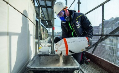 Maçon manipulant des produits chimiques sur un chantier.