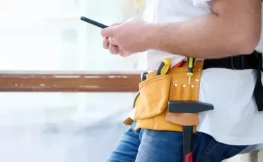 Artisan utilisant son smartphone pour un suivi de chantier.
