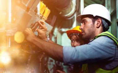 Technicien de maintenance intervenant sur des conduites industrielles dans une usine.