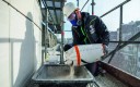 Maçon manipulant des produits chimiques sur un chantier.