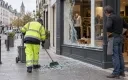 Agent municipal nettoyant devant une boutique endommagée